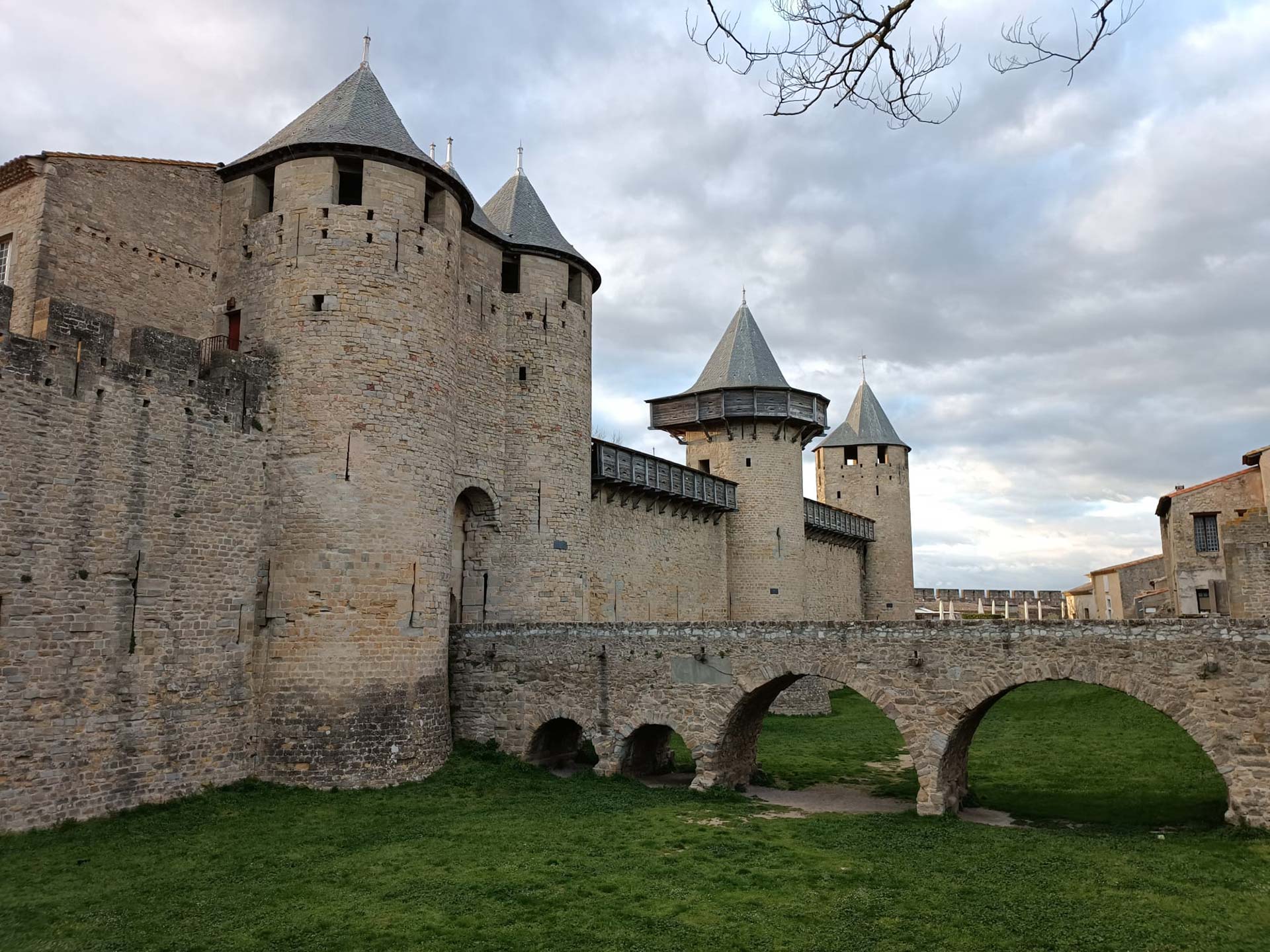 Pont d'entrada, amb fossat a sota ple de gespa i muralla amb torres de Carcassonne.